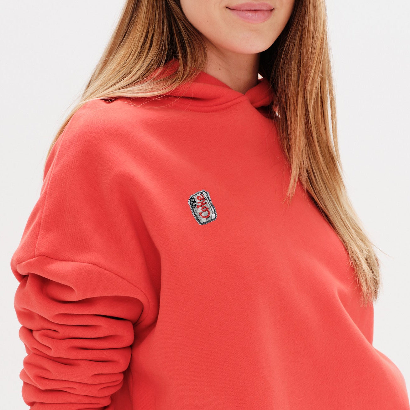 Person wearing an Orange hoodie with a small diet coke embroidery on a white background