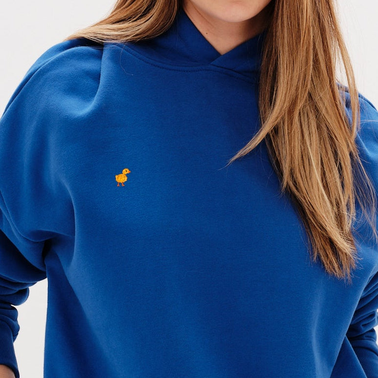 Woman wearing a premium blue hoodie with a duck embroidery