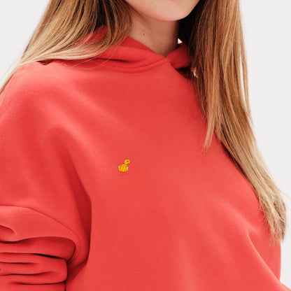 Woman wearing a premium orange hoodie with a duck embroidery