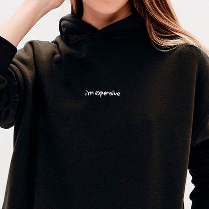 Woman wearing a black hoodie with an I'm expensive embroidered text 