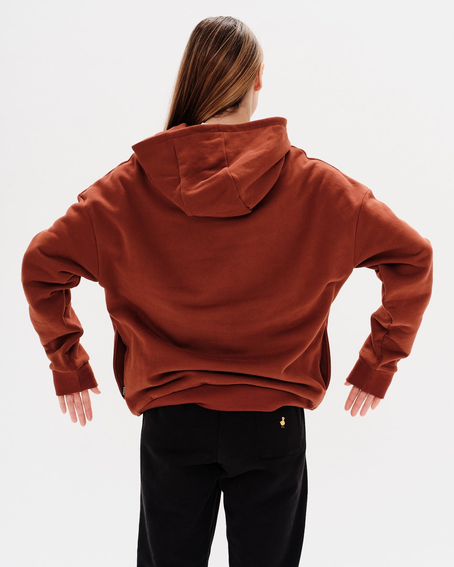 Woman wearing a brown hoodie with an I'm expensive embroidered text 