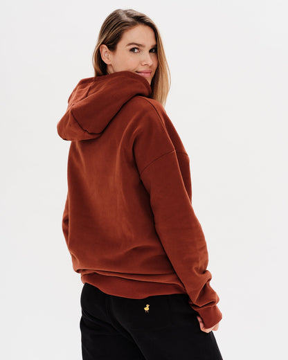 Woman wearing a brown hoodie with an I'm expensive embroidered text 