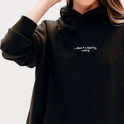 Woman wearing a black sweatshirt with I don't want to work embroidery text