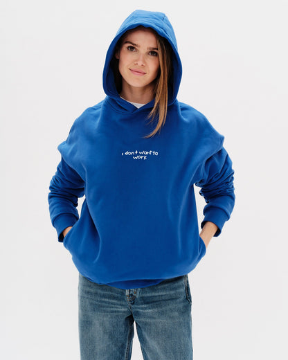 Woman wearing a blue sweatshirt with I don't want to work embroidery text