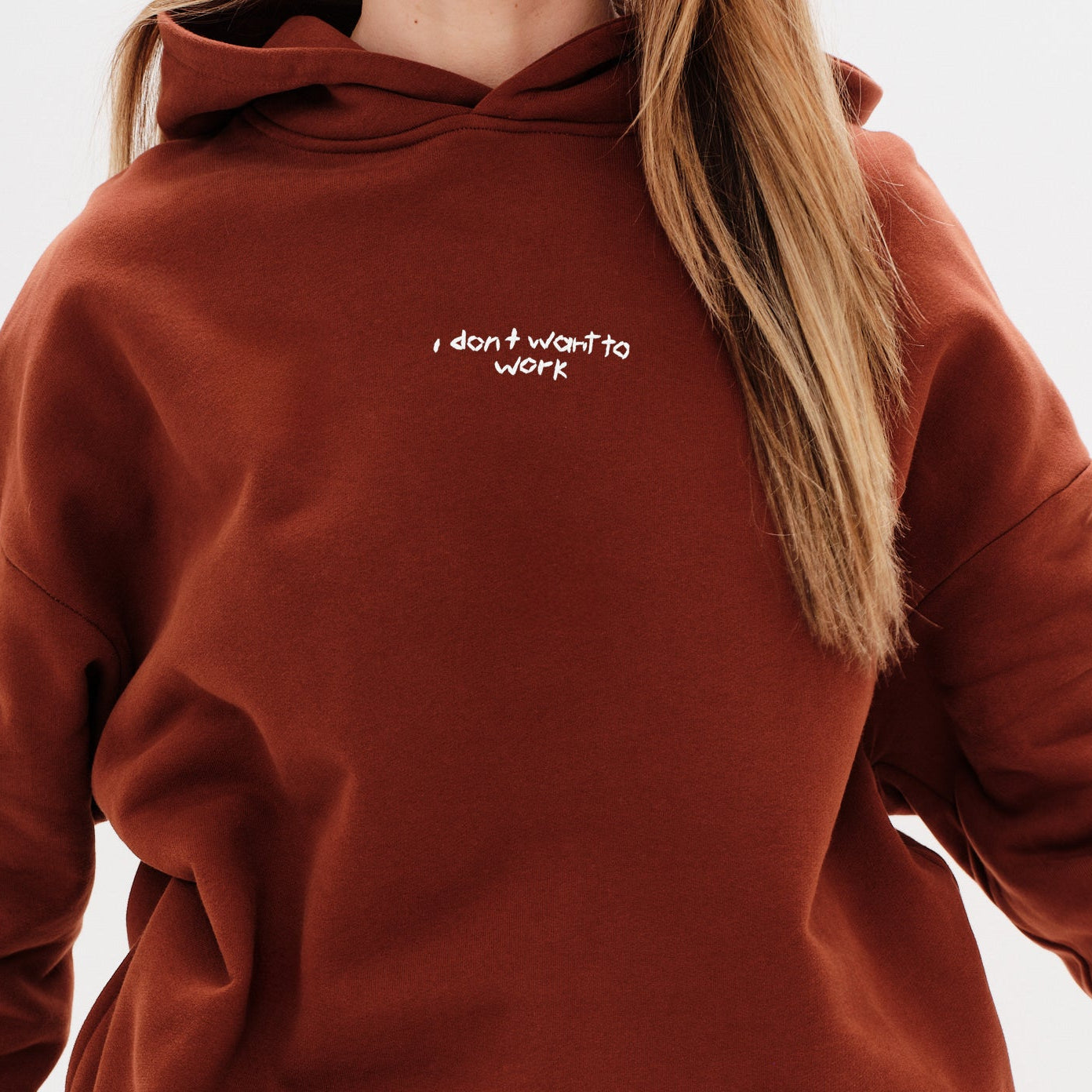 Woman wearing a brown sweatshirt with I don't want to work embroidery text