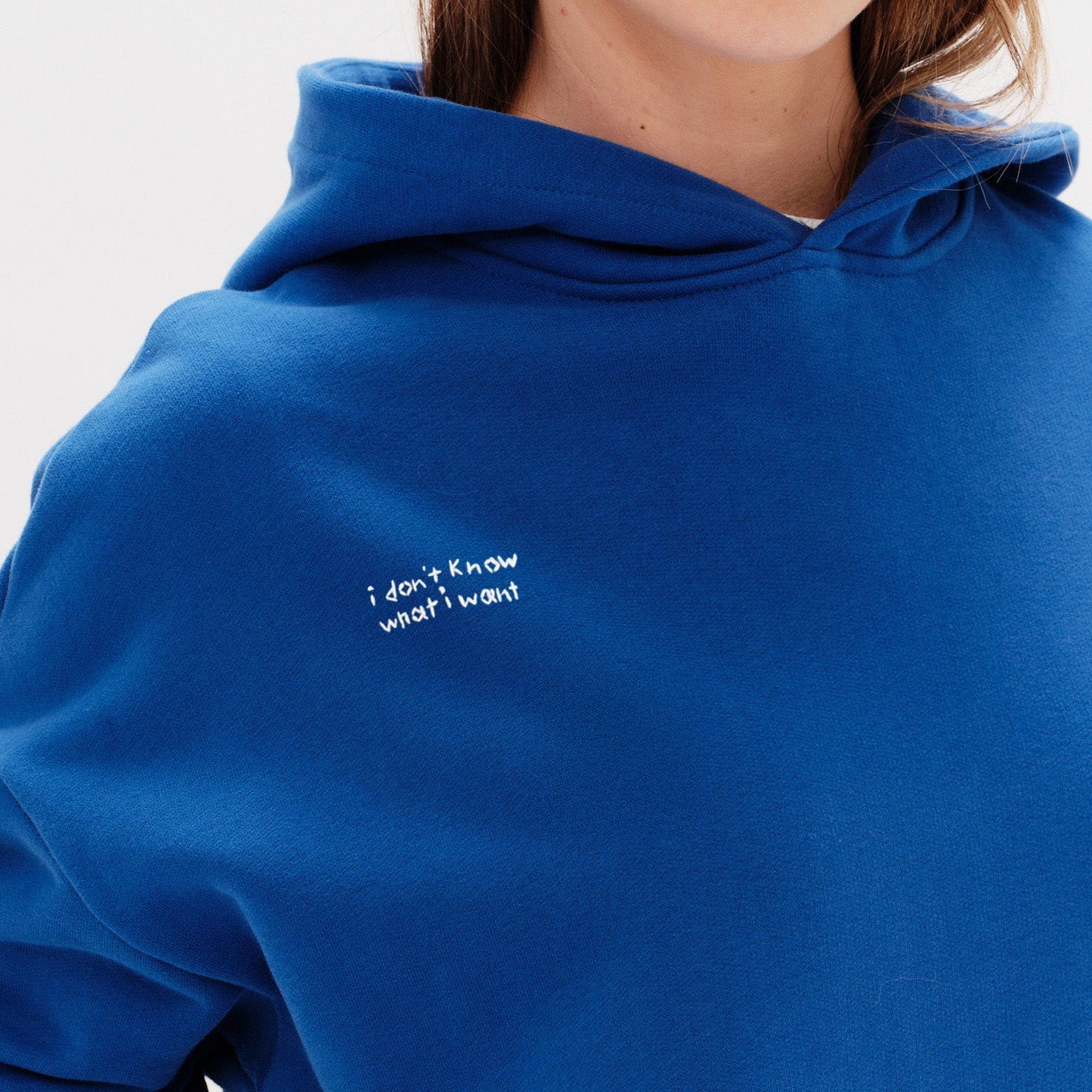 Woman wearing a blue hoodie with an I don't know what I want embroidery text