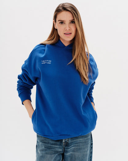 Woman wearing a blue hoodie with an I don't know what I want embroidery text