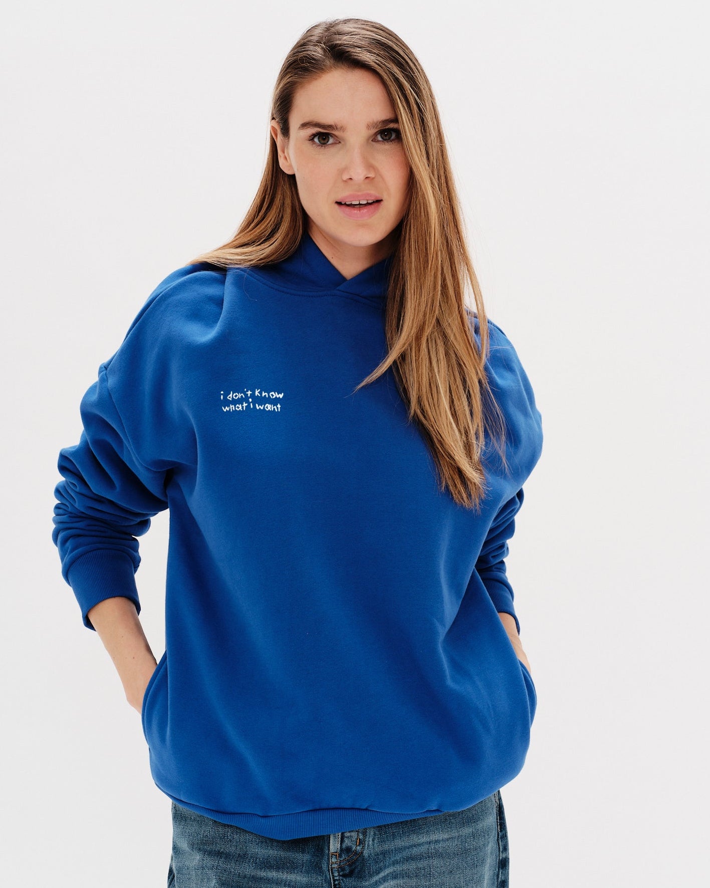 Woman wearing a blue hoodie with an I don't know what I want embroidery text