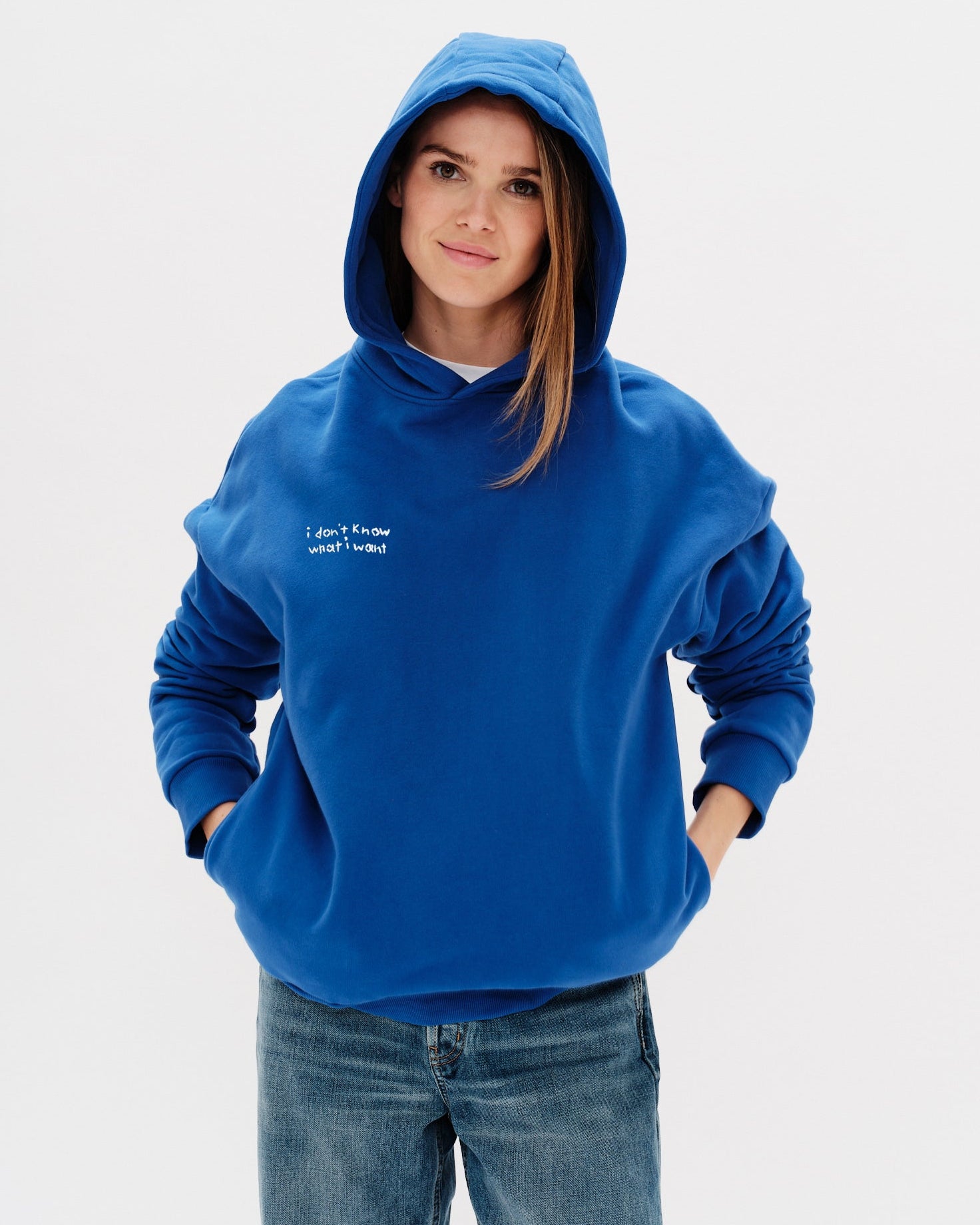 Woman wearing a blue hoodie with an I don't know what I want embroidery text