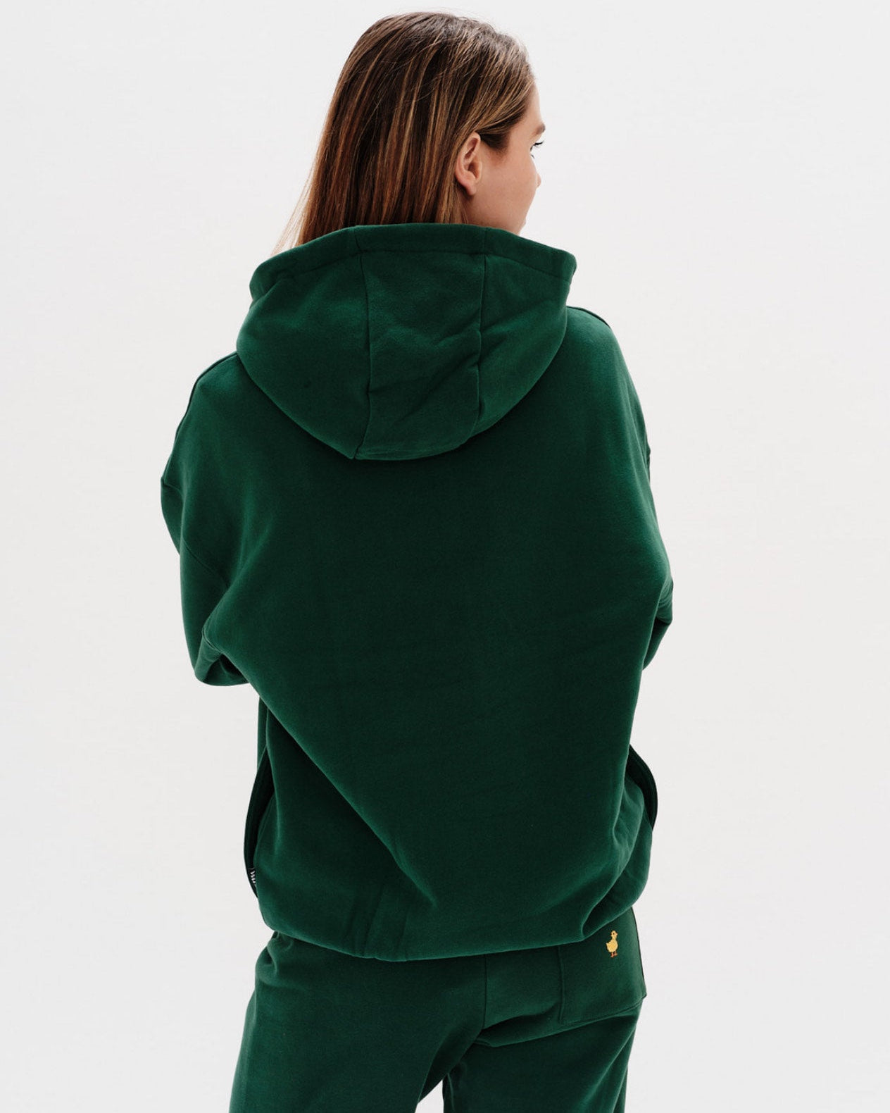 Person wearing a green hoodie and pants on a white background