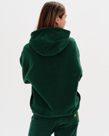 Person wearing a green hoodie and pants on a white background