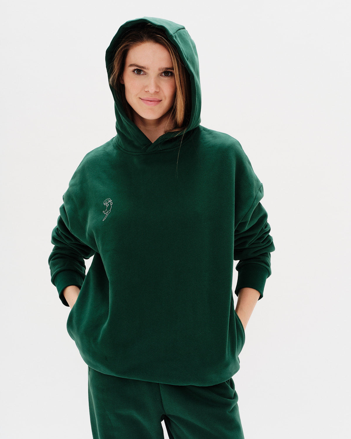 Person wearing a green hoodie and pants on a white background
