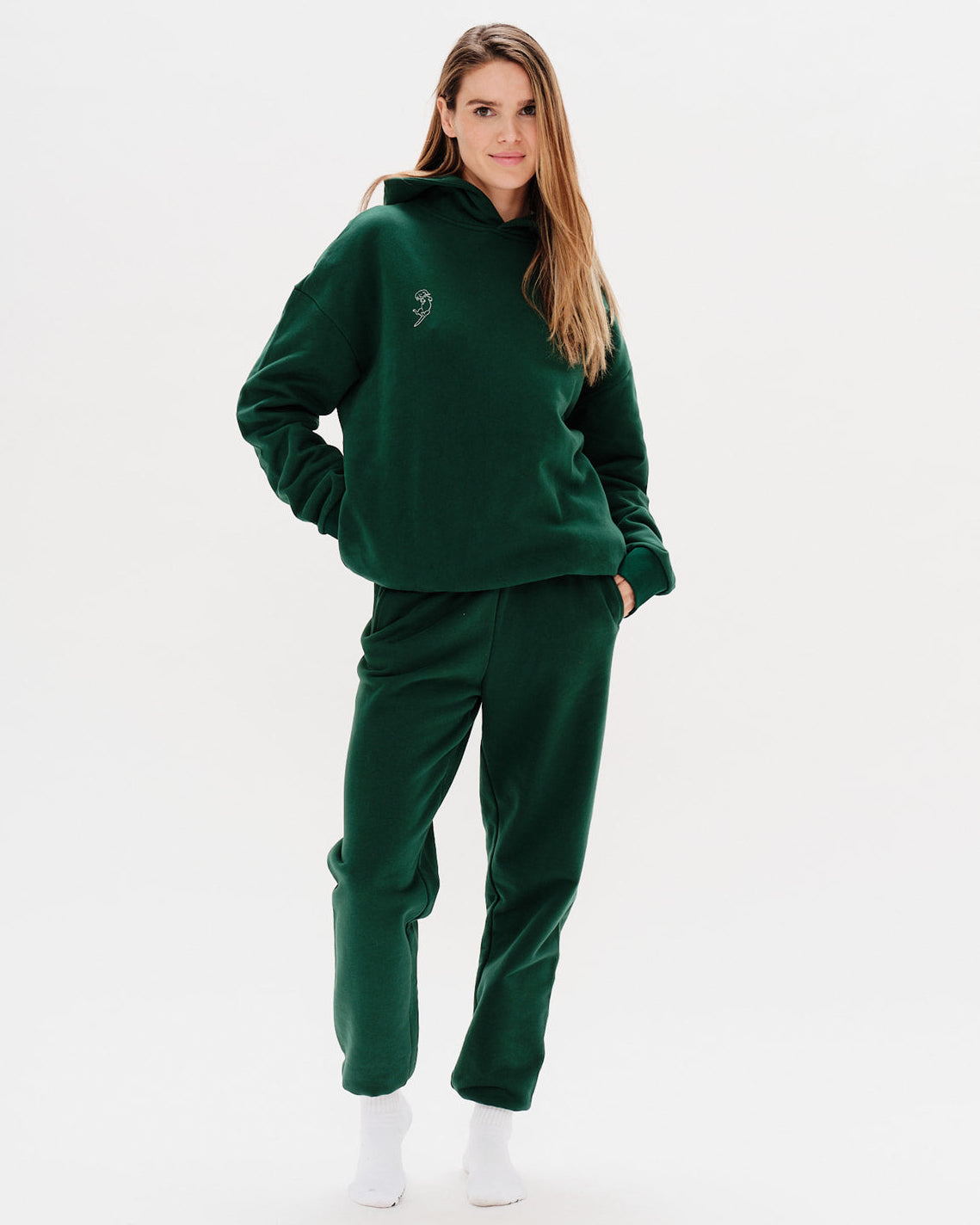 Woman wearing a green hoodie and pants on a white background