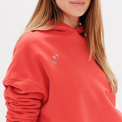 Person wearing a red hoodie with a wiener dog embroidery design 