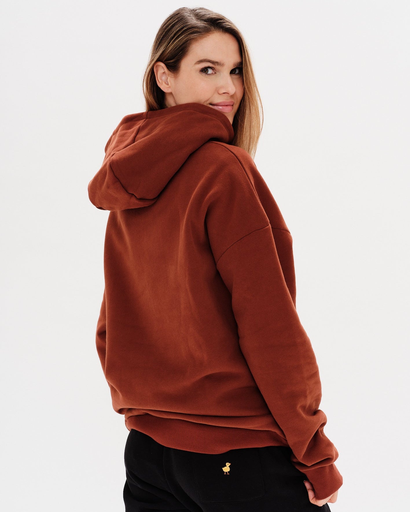 Woman wearing a brown premium hoodie with a mini duck embroidery
