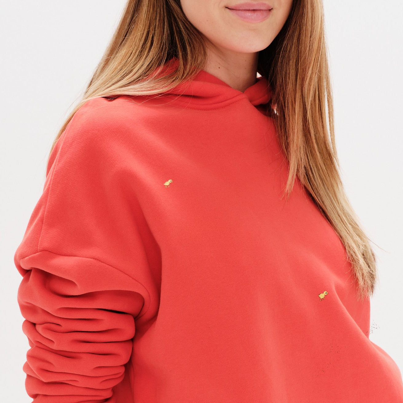 Woman wearing an orange premium hoodie with a mini duck embroidery