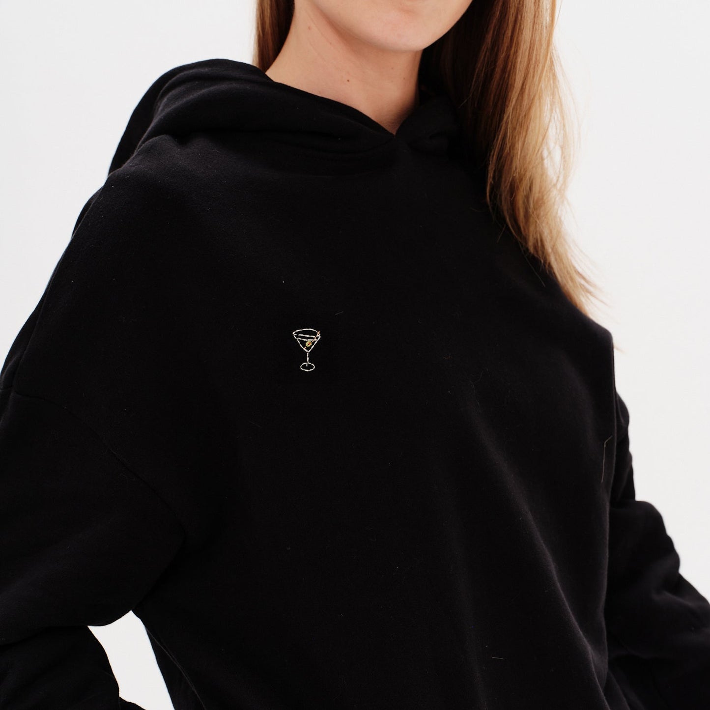 Woman wearing a premium black hoodie with a martini emboridery