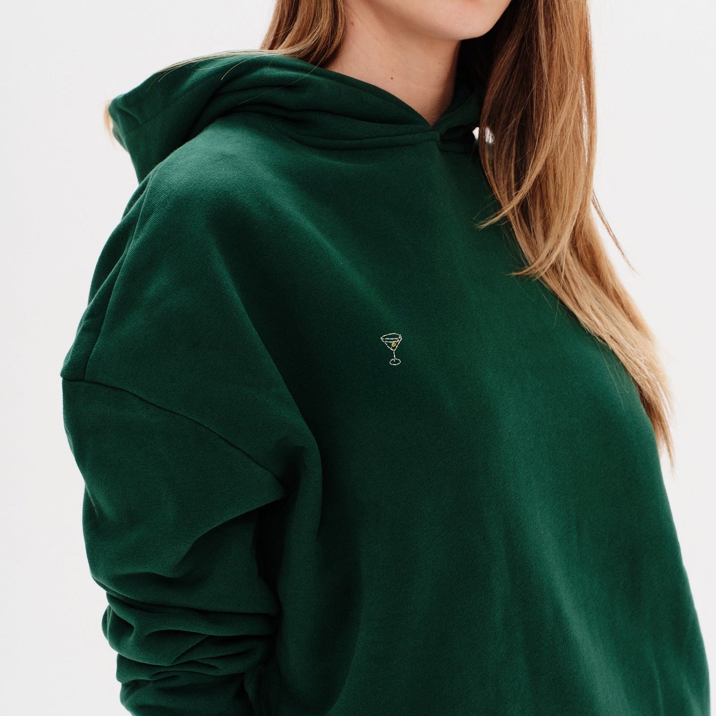 Woman wearing a premium green hoodie with a martini emboridery