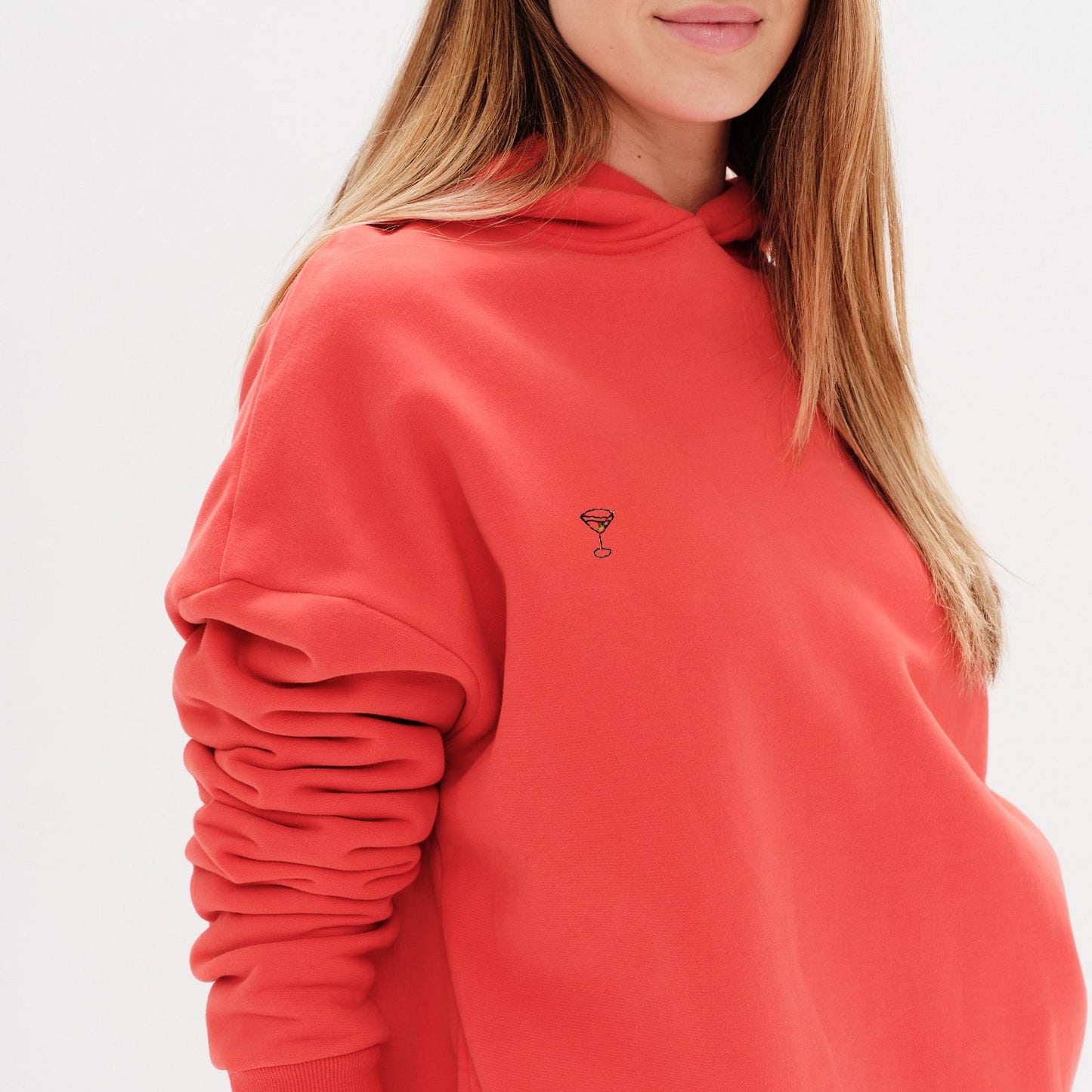 Woman wearing a premium orange hoodie with a martini emboridery