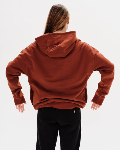 Woman wearing a brown hoodie with a New York Boy embroidery text