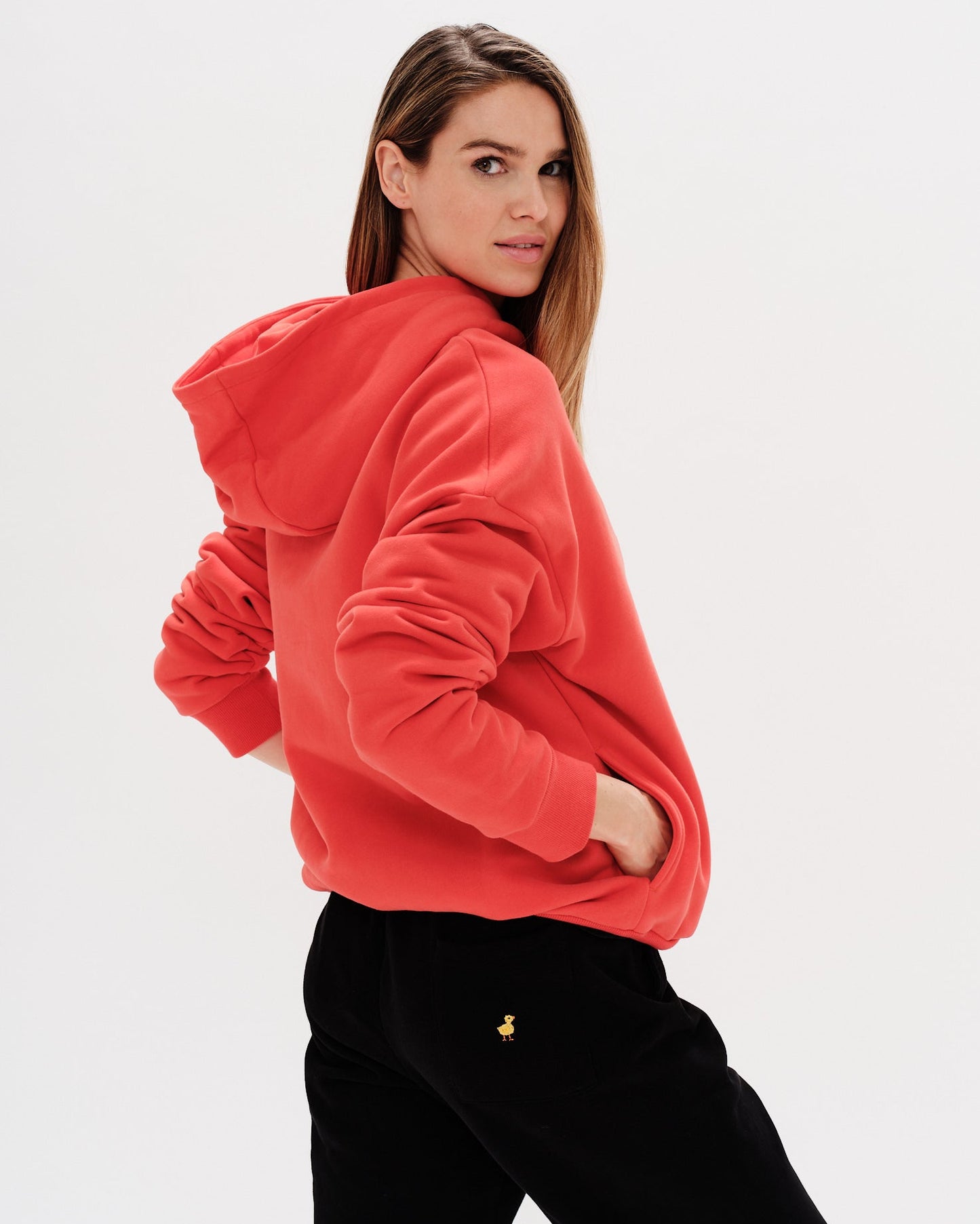 Woman wearing an orange hoodie with a New York Girl embroidery.