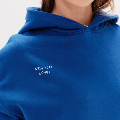 Woman wearing a blue hoodie with New York Lover embroidery text