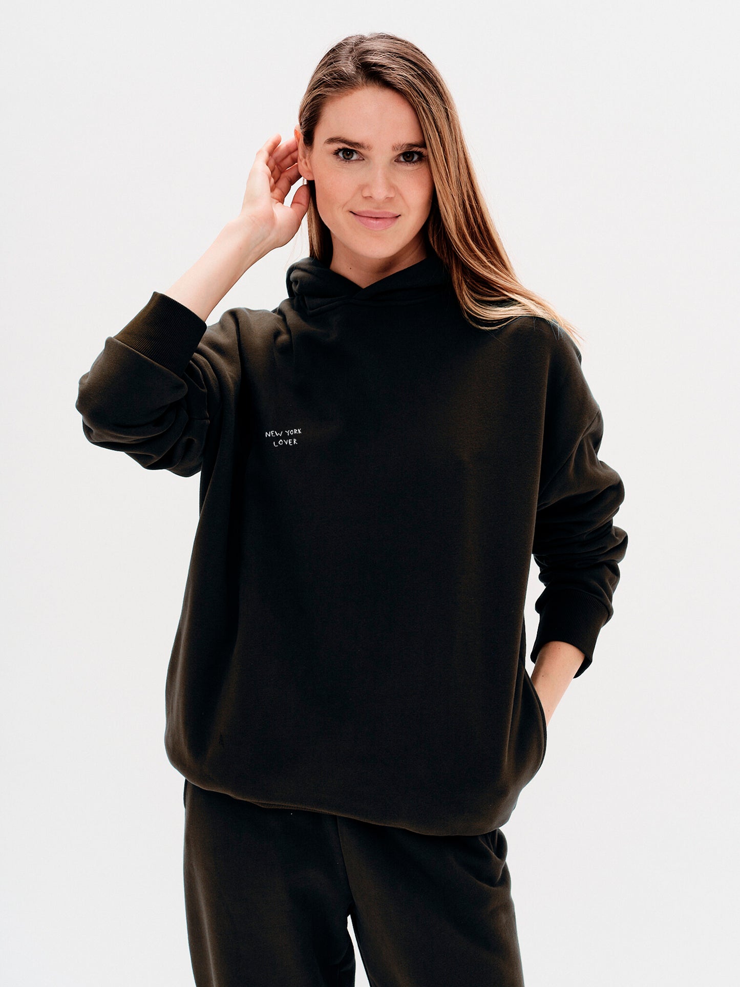 Woman wearing a black hoodie with New York Lover embroidery text