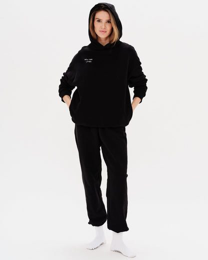 Woman wearing a black hoodie with New York Lover embroidery text