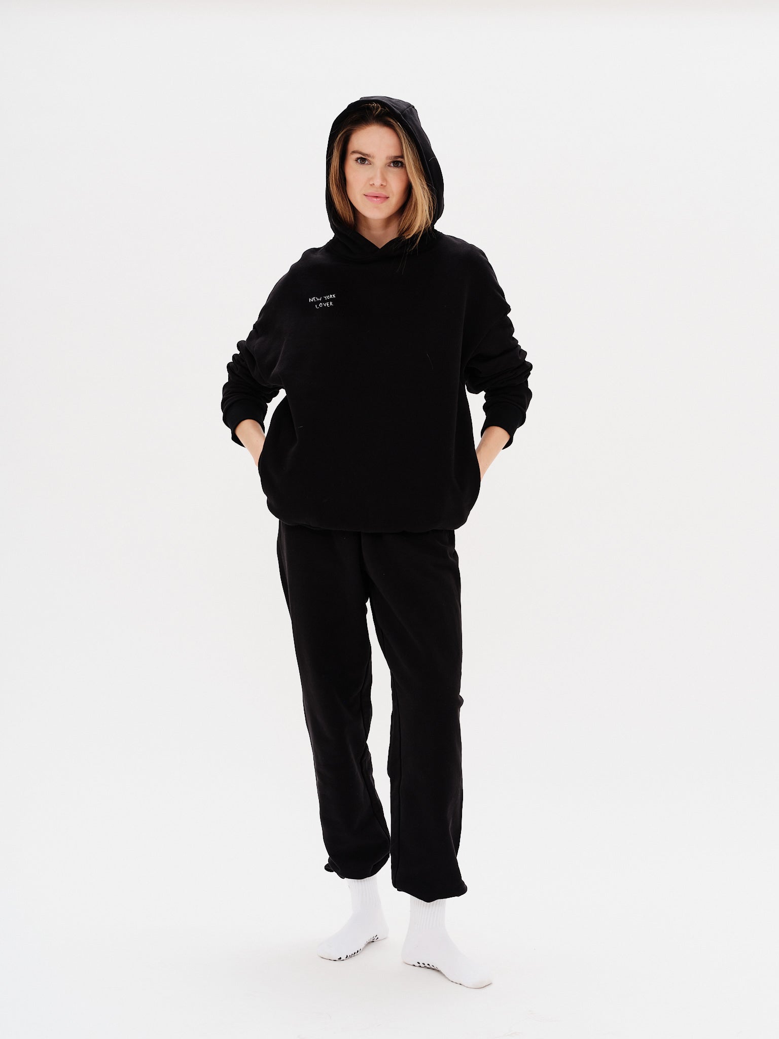 Woman wearing a black hoodie with New York Lover embroidery text
