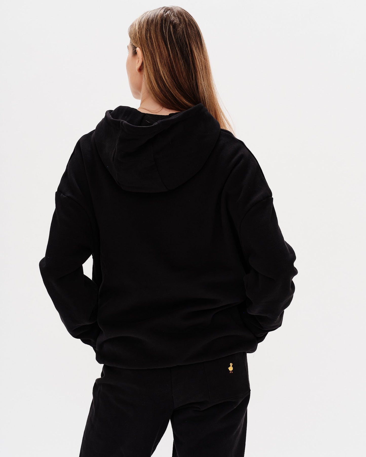 Woman wearing a black hoodie with New York Lover embroidery text