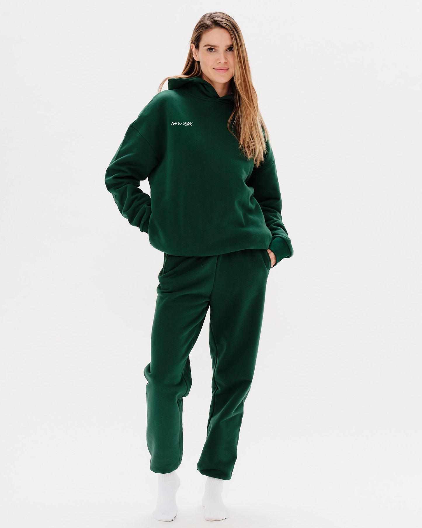 Woman wearing a green premium hoodie with a 'New York' embroidery