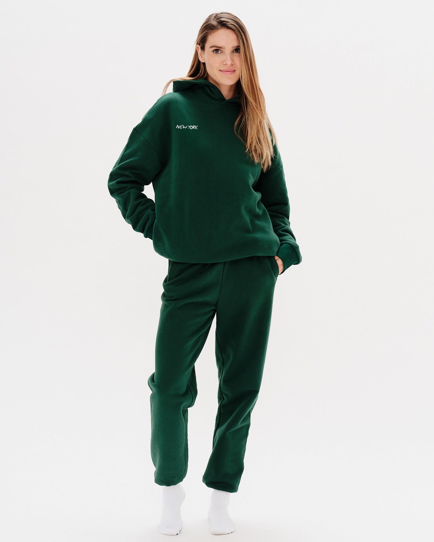 Woman wearing a green premium hoodie with a 'New York' embroidery