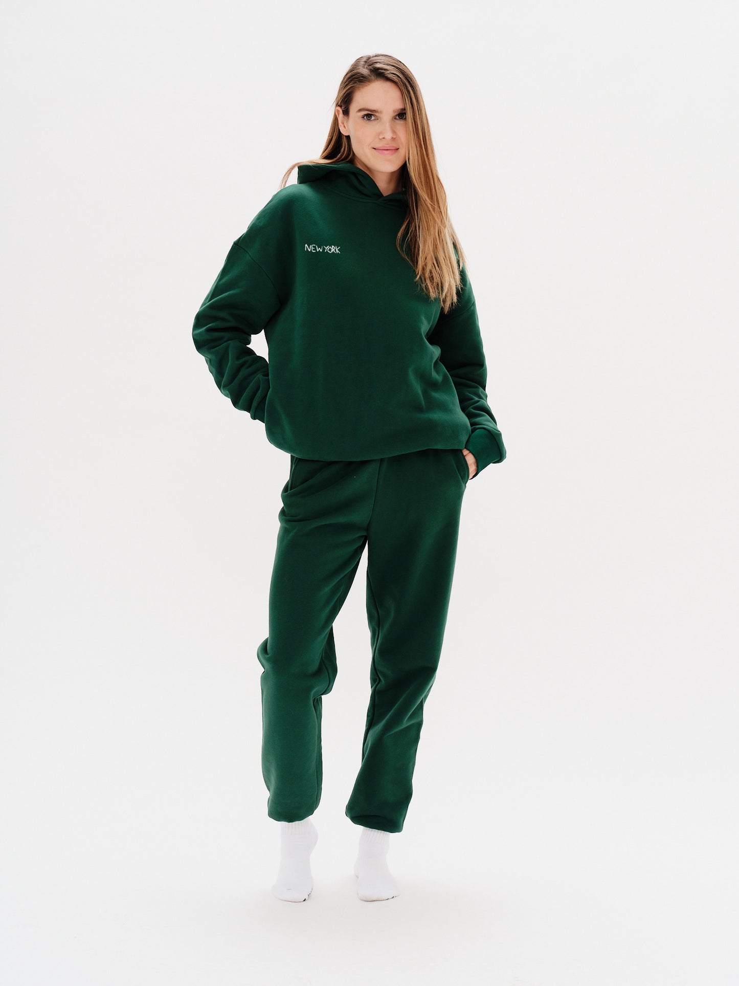 Woman wearing a green premium hoodie with a 'New York' embroidery