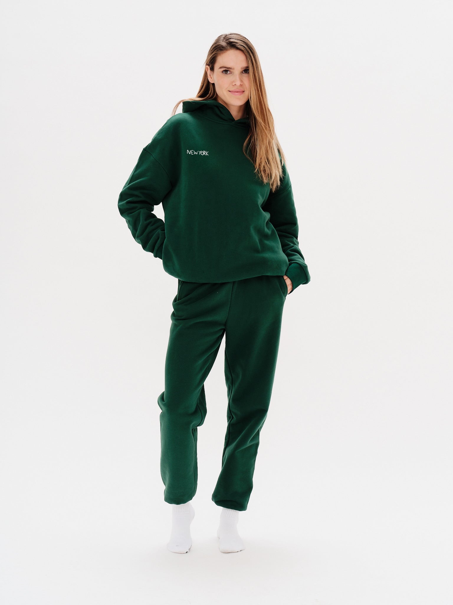 Woman wearing a green premium hoodie with a 'New York' embroidery