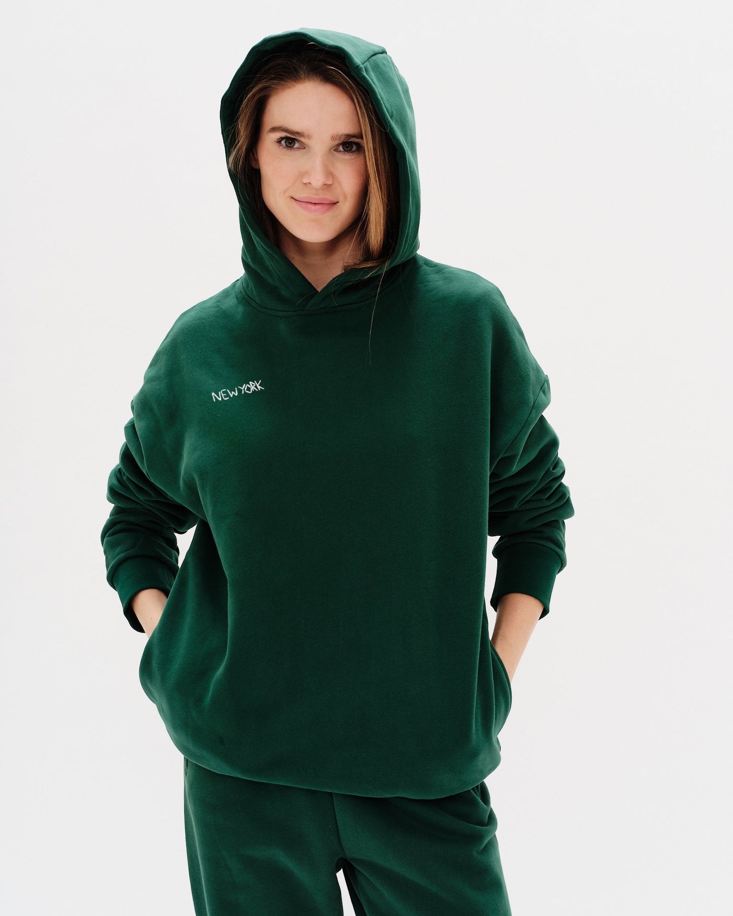 Woman wearing a green premium hoodie with a 'New York' embroidery