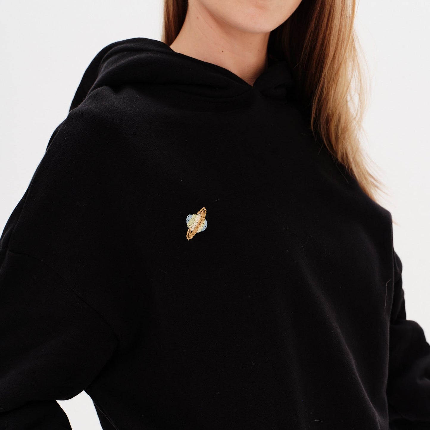 Woman wearing a premium black hoodie with a planet embroidery