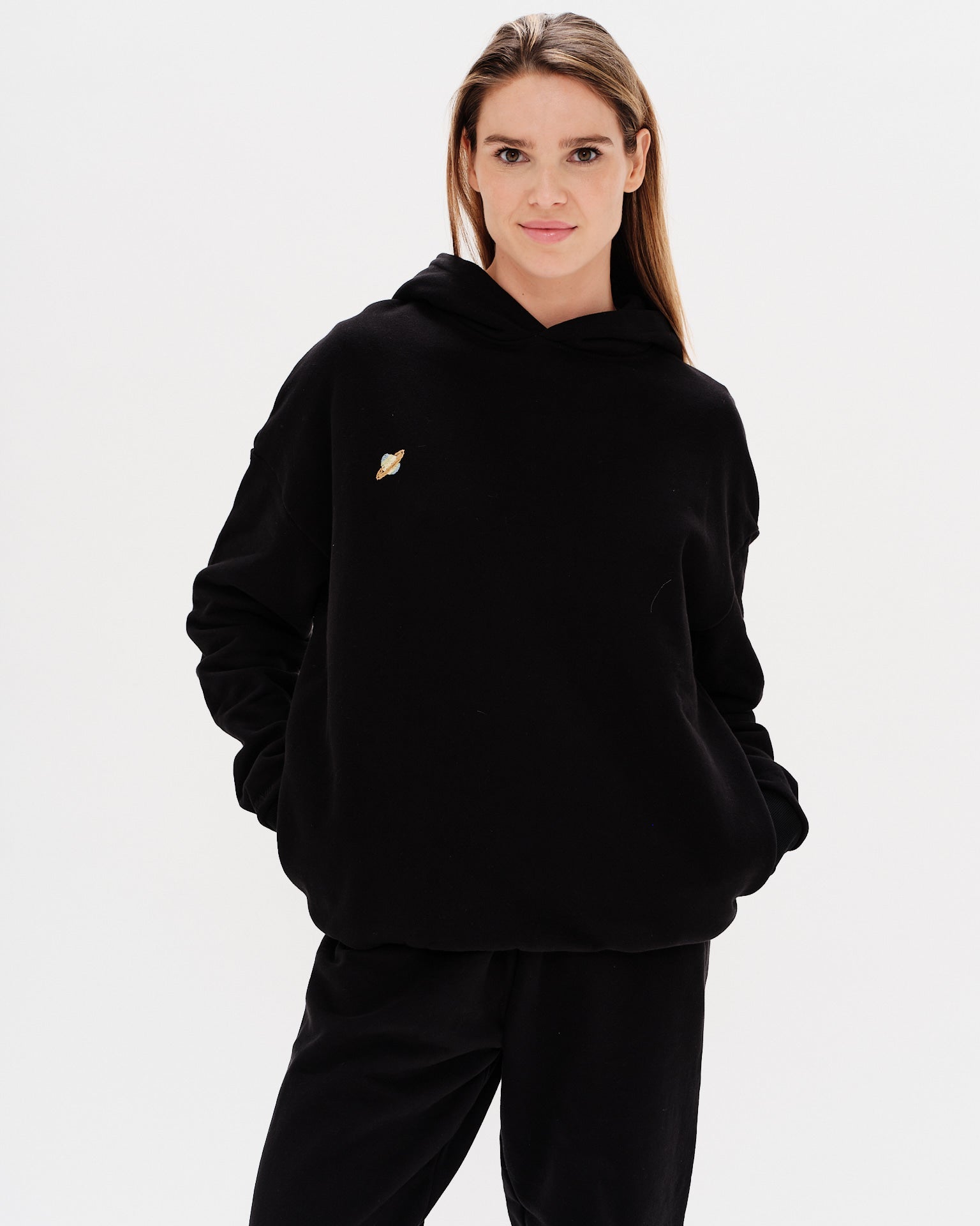 Woman wearing a premium black hoodie with a planet embroidery