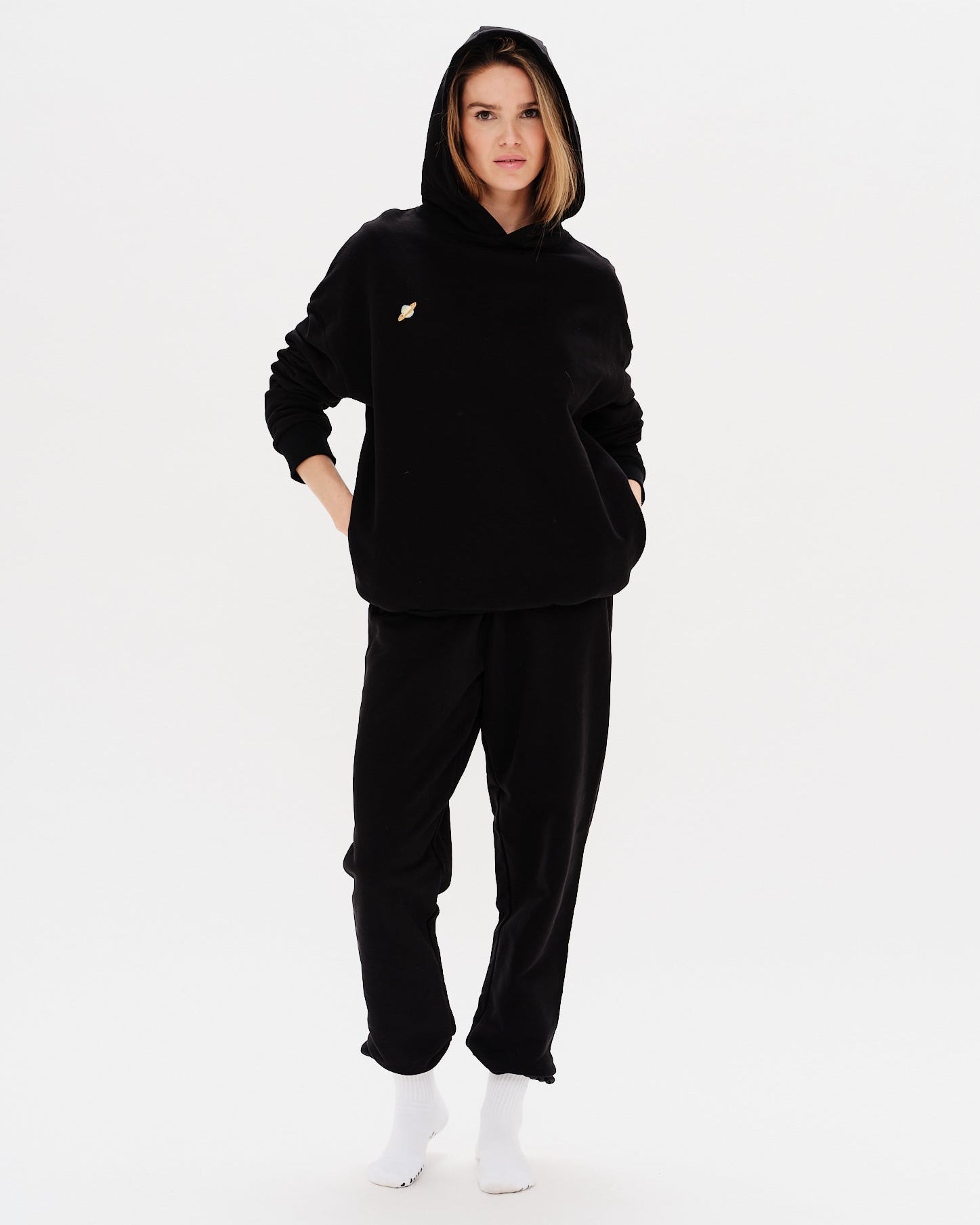 Woman wearing a premium black hoodie with a planet embroidery