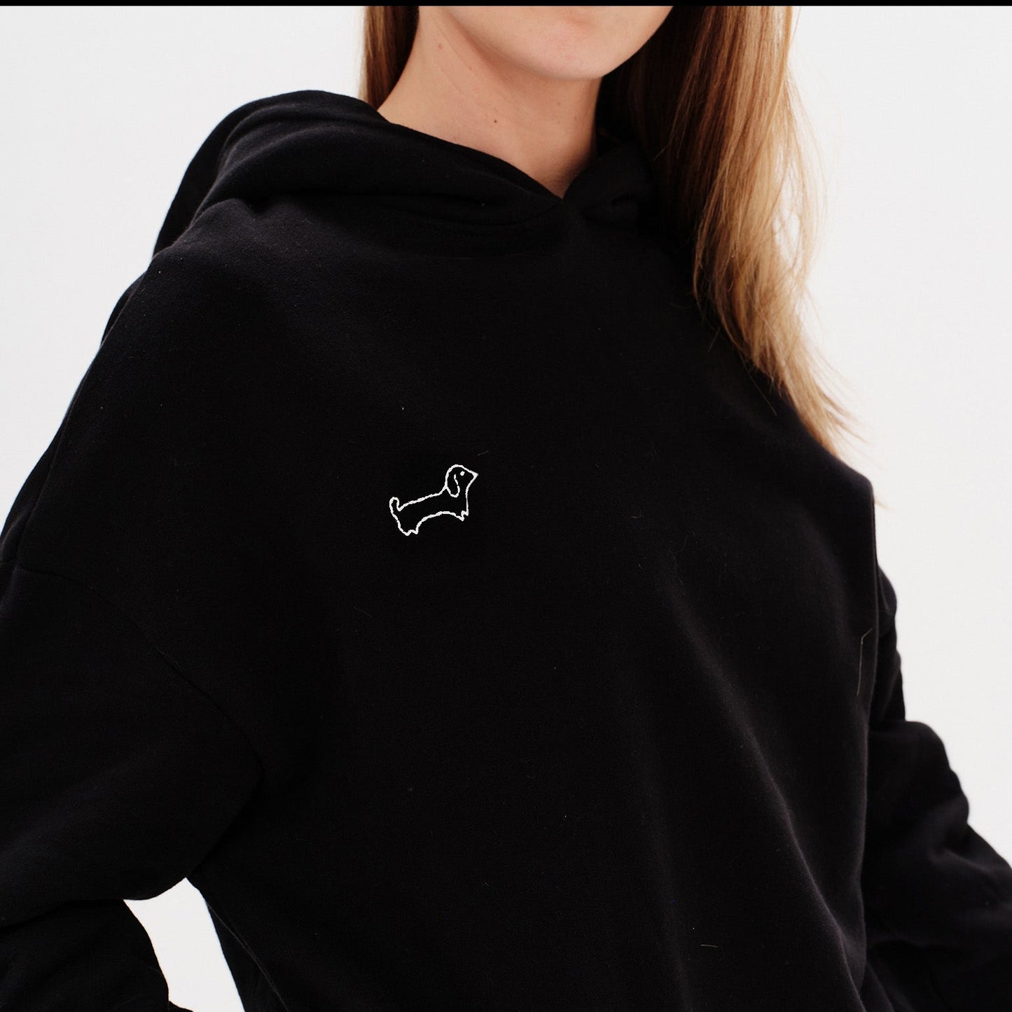 Woman wearing a black hoodie with a wiener dog embroidery