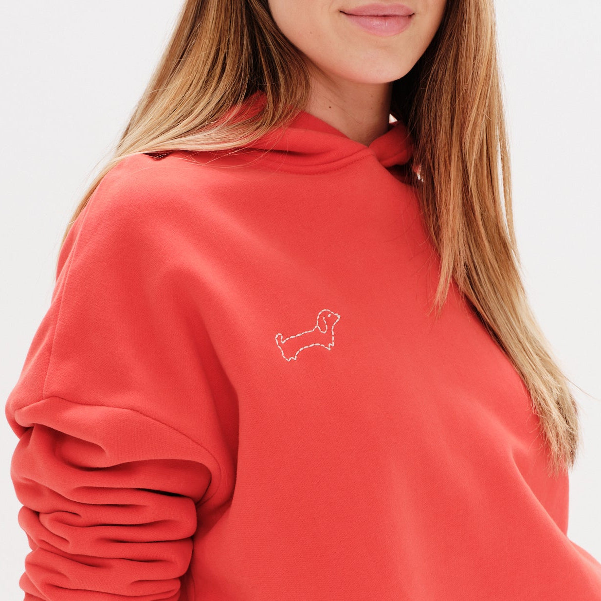 Woman wearing a red hoodie with a wiener dog embroidery