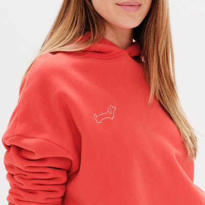 Woman wearing a red hoodie with a wiener dog embroidery