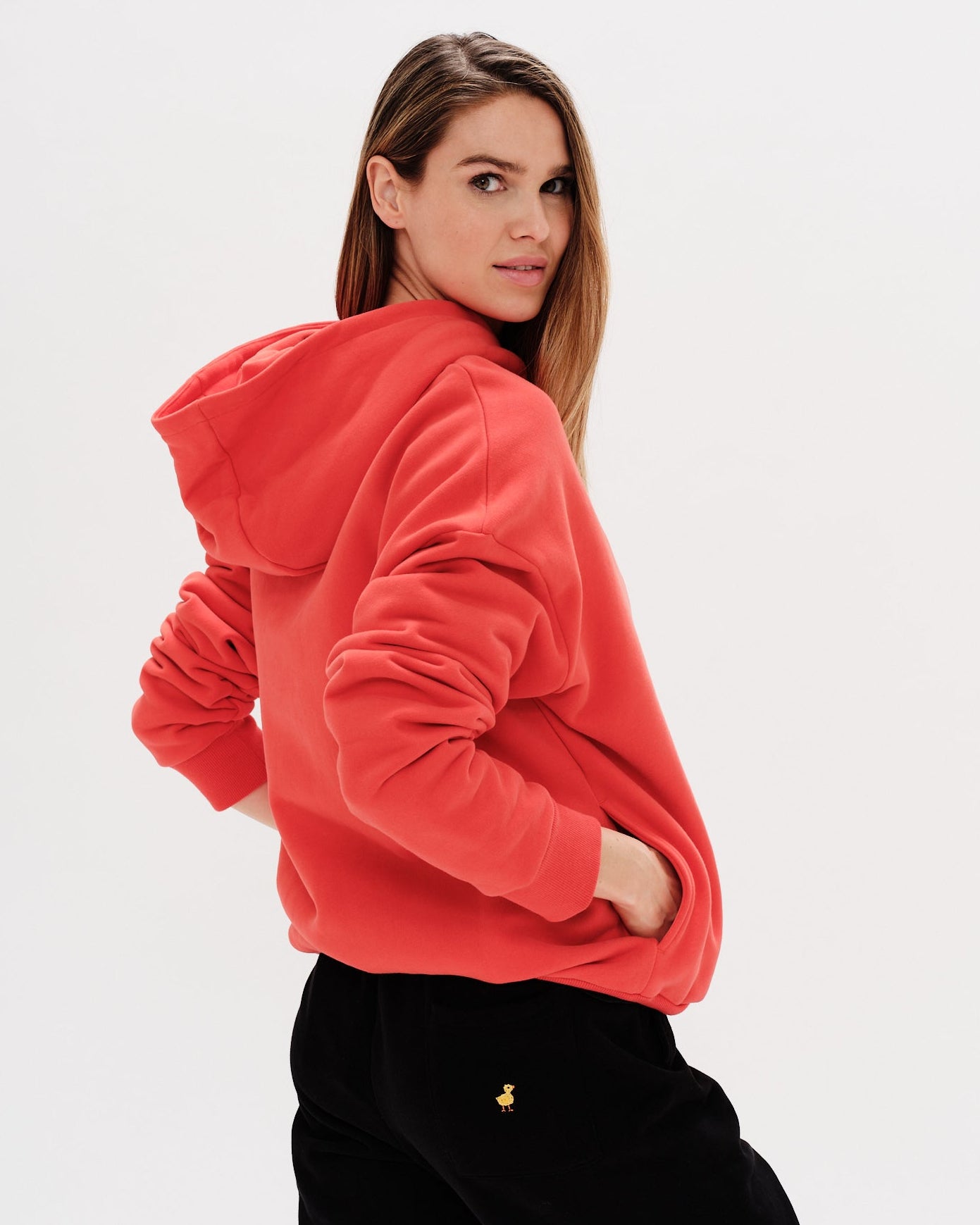 Woman wearing a red hoodie with a wiener dog embroidery
