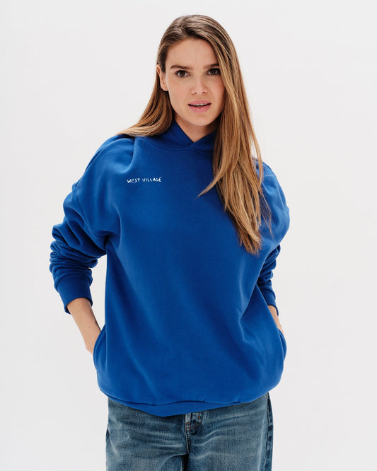 Woman wearing a blue hoodie with a 'West Village' embroidery 