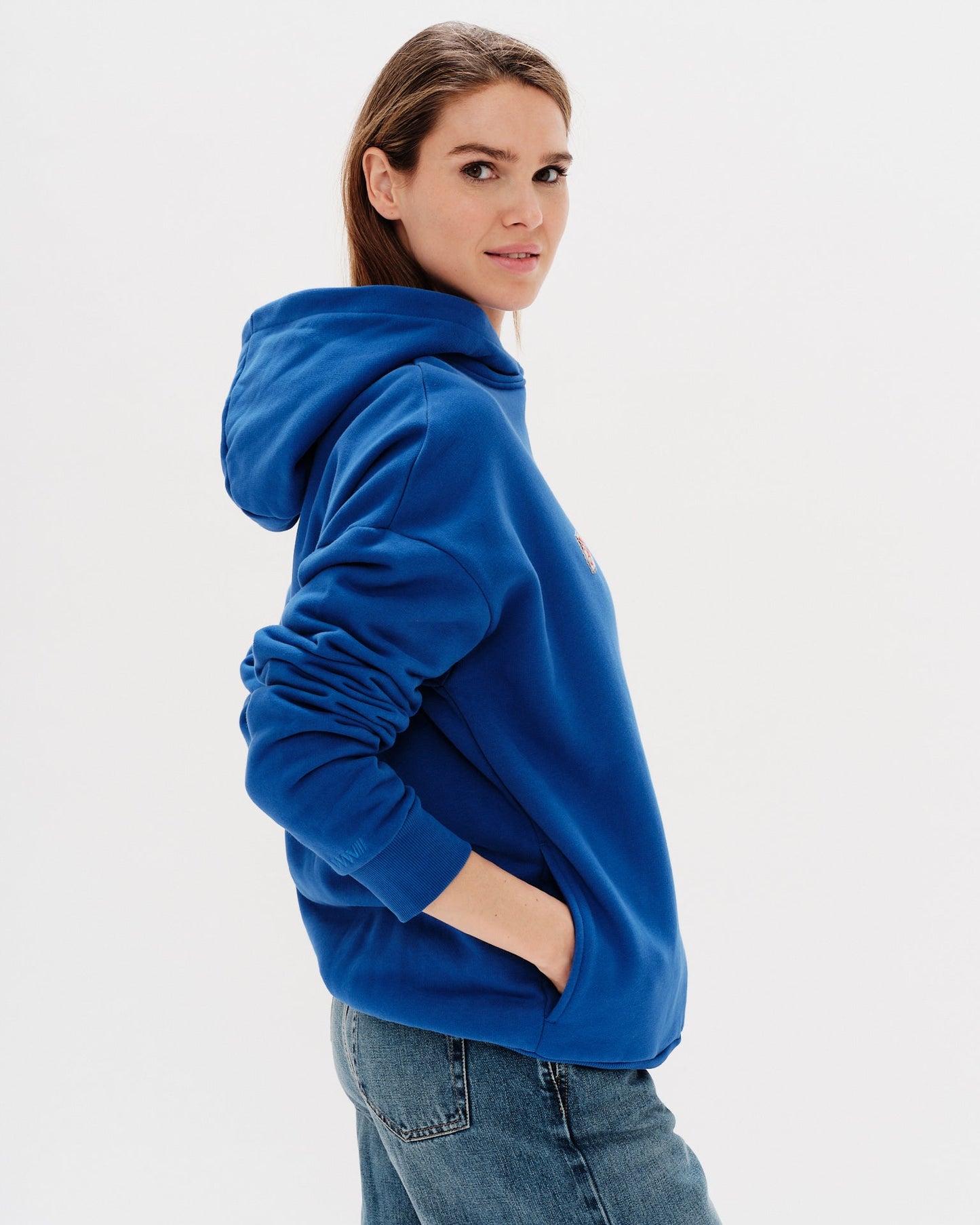 Woman wearing a blue hoodie with a 'West Village' embroidery 