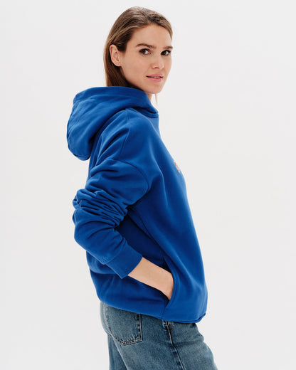 Woman wearing a blue hoodie with a 'West Village' embroidery 