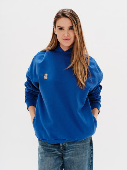 Woman wearing a blue sweatshirt with a small diet coke embroidery on a white background