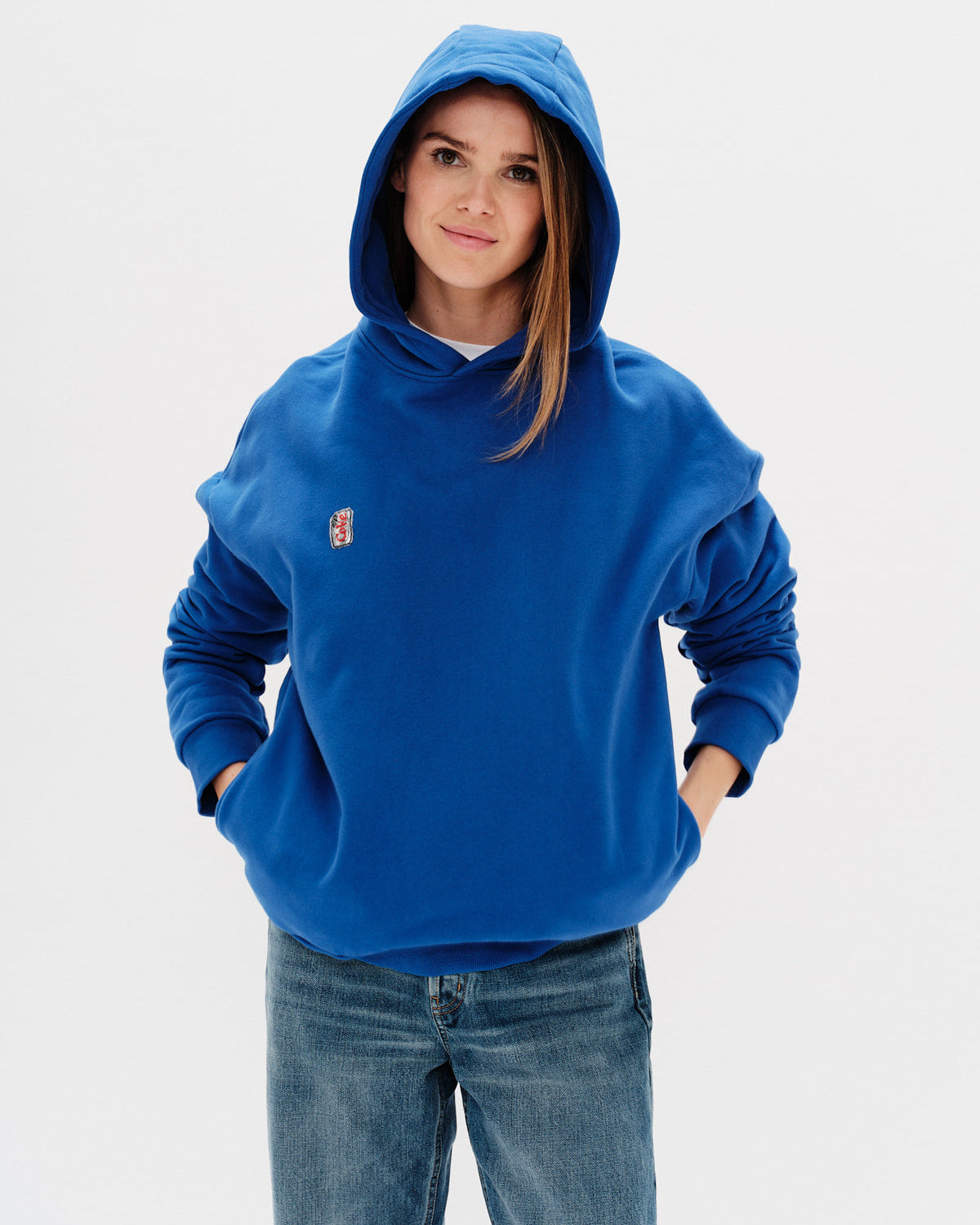 Person wearing a blue hoodie with a small diet coke embroidery on a light gray background
