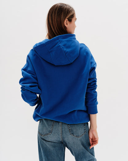 Person wearing a blue hoodie and jeans on a white background