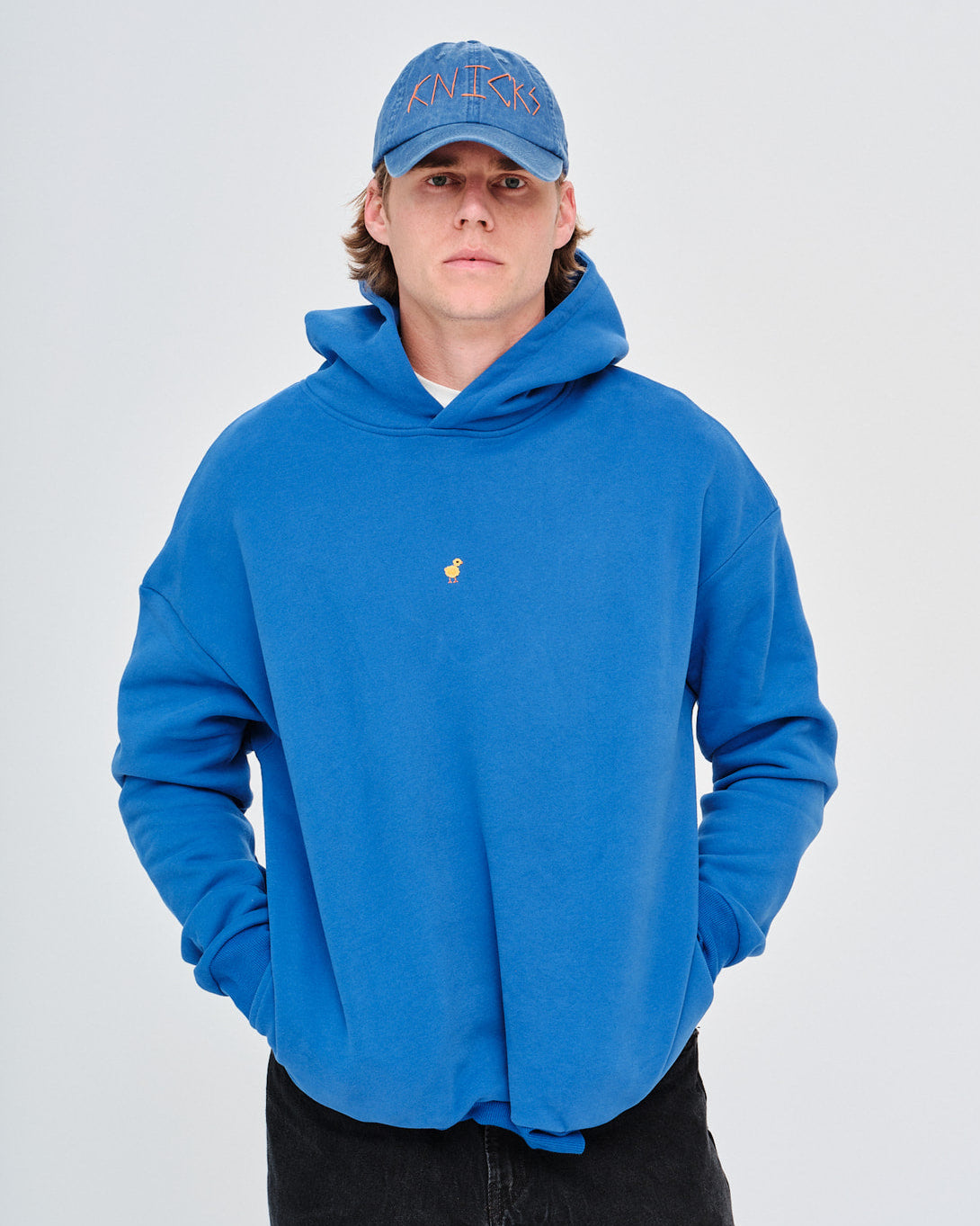 Man wearing a blue hoodie with a small duck embroidery