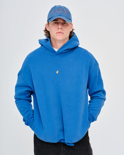Man wearing a blue hoodie with a small duck embroidery